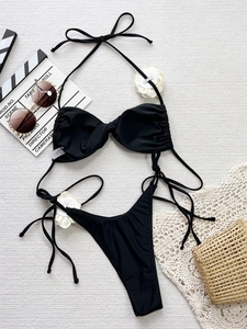 Flat lay of black halter neck bikini set with side-tie bottoms and beach vacation decor