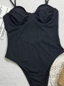 Detailed view of black ribbed one-piece bikini with thin straps and ruched chest design