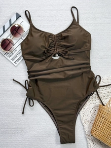 Costume intero marrone con cut-out e lacci arricciati su sfondo con accessori mare