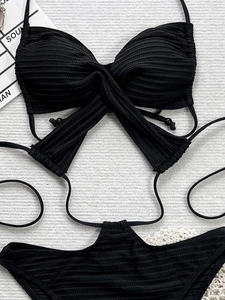 Vue détaillée du tissu côtelé noir et du design à bretelles croisées du haut de bikini