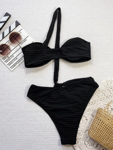Flat lay of black ribbed monokini with cut-out detail and summer vacation accessories