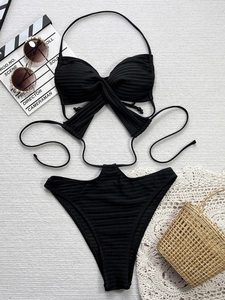 Détail d'un bikini côtelé noir avec licou et culotte haute sur tapis de plage texturé