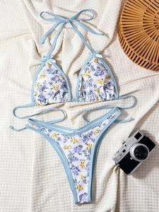 Flat lay of floral bikini with halter neck, bow detail and vintage camera decor