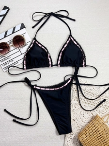 Close-up of black bikini set featuring pink ribbon lace-up trim and detailed lace edges