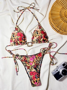 Detail of leopard floral print bikini with metallic gold rings on waffle texture cloth