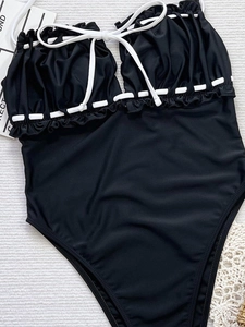 Détail d'un maillot de bain noir avec nœud blanc et finitions à volants délicats