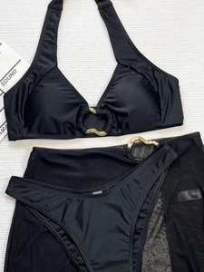 Detailed flat lay of black three-piece bikini set with gold metal ring and mesh sarong