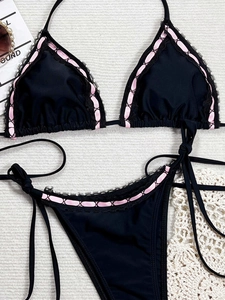 Detailed flat lay of black bikini set with lace trim and pink ribbon bow accents