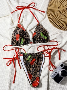 Flat lay of leopard and cherry print bikini with red tie straps on waffle fabric