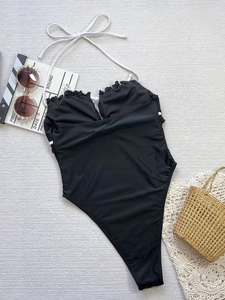 Vue détaillée d'un maillot de bain noir avec bretelles blanches et décolleté à volants