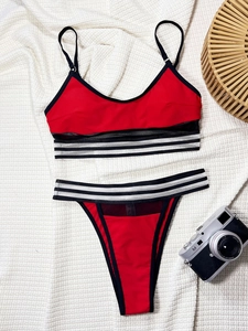 Flat lay of red two-piece bikini with mesh panels and black white striped elastic bands