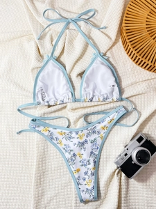 Flat lay of floral bikini set with blue trim and detailed size tag on waffle fabric