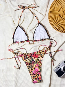 Detail of leopard and floral print bikini with golden heart rings on white knit