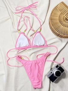 Flat lay of pink halter bikini set with colorful beads on textured waffle background