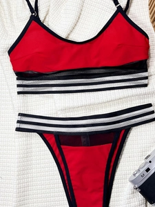 Detailed flat lay of a red two-piece bikini featuring mesh panels and striped elastic bands