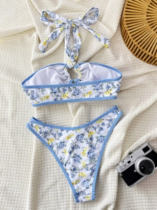 Flat lay of floral bikini with high-cut bottoms and retro accessories on textured linen