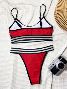 Flat lay of a red and white bikini set with checkered trim and a vintage camera accessory