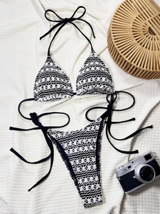 Detailed flat lay of a black and white crochet bikini with chic summer vacation props