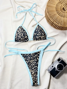 Sexy leopard print bikini set with light blue trim on a summer vacation flat lay background