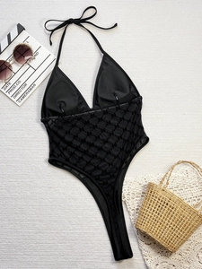 Flat lay of black halter one-piece swimsuit with mesh panel and letter jacquard details