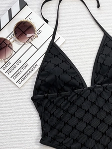 Detail of black halter swimsuit featuring mesh texture and pearl-rimmed sunglasses