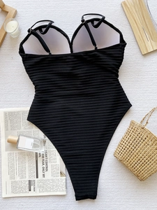 Chic black ribbed one-piece swimsuit with thin straps on elegant vacation background