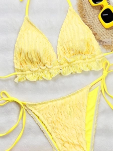 Vibrant yellow ruffled bikini set with textured fabric and matching summer accessories