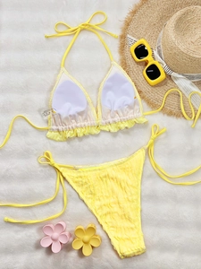 Solid yellow ruffled bikini set with halter top and side-tie bottoms on faux fur backdrop