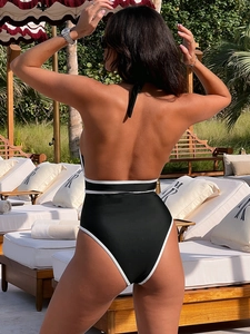 Vista posteriore di un costume intero nero con bordi bianchi e schiena scoperta al sole