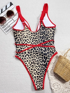 One-piece leopard print swimsuit with red trim and cross-strap waist detail