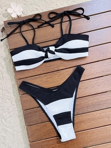 Flat lay of black and white striped bikini with crinkle texture on a beach wood background