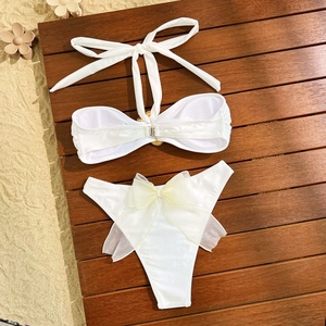 Détail de bikini blanc avec boucle en métal et grand nœud en organza au dos du bas