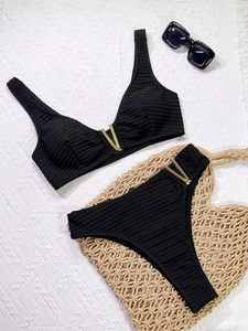 Detailed view of black ribbed bikini fabric featuring a chic gold V-shaped hardware accent
