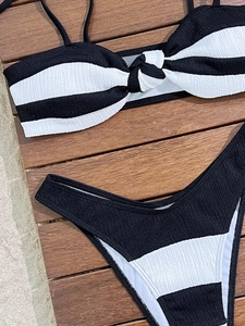 Flat lay of black and white striped bikini with textured seersucker fabric on wood