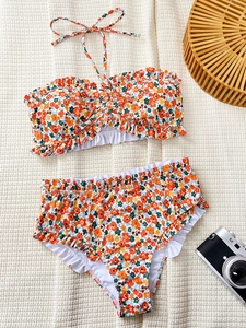 Flat lay of floral bikini with ruffled edges, wooden bag and retro camera on white background