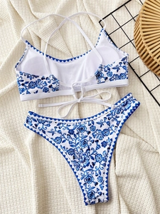 Detail shot of floral print bikini with blue scalloped trim on white textured background