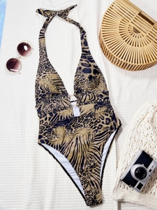 Dettaglio costume intero animalier con apertura a V in perle e accessori da spiaggia