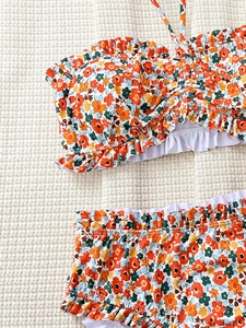 Detailed view of floral bikini fabric texture with ruffle edges and orange blossoms