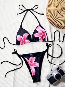 Two-piece black bikini set with pink lily floral print and side-tie triangle bottom