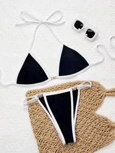 Flat lay of black and white bikini with gold hardware and summer accessories
