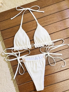 Detail of white smocked bikini with textured fabric and golden decorative metal rings
