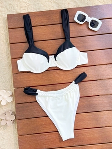 Bikini bicolore noir et blanc posé à plat avec lunettes de soleil sur terrasse de plage