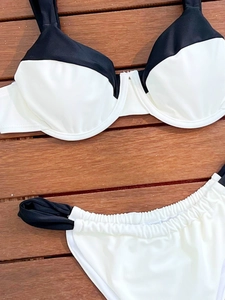 Vue détaillée d'un bikini bicolore noir et blanc avec bonnets à armatures sur bois