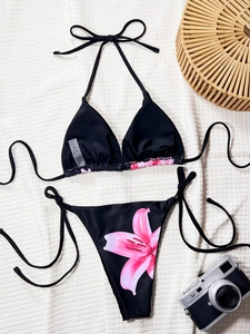 Solid black bikini set with pink lily print on side tie bottoms and vacation accessories