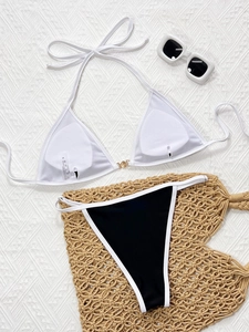 Flat lay of white halter bikini top with gold buckle and black-white contrast bottoms