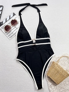 Dettaglio del costume intero nero con bordo bianco, scollo all'americana e fibbie di perle