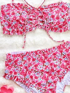 Close-up of pink floral bikini set with ruffled edges on a soft plush white background