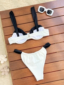 Ensemble bikini bicolore noir et blanc posé à plat sur bois avec lunettes pour les vacances