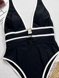 Dettaglio del costume intero nero con bordini bianchi e fibbie decorate con perle