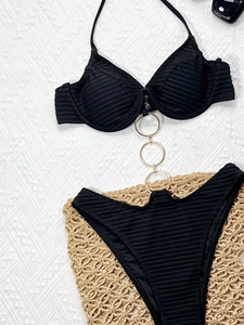 Detailed view of black ribbed swimsuit with three vertical gold metal ring connectors